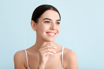 Beautiful young woman with healthy skin on color background