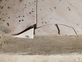 a cracked ceramic tiles floor surface due to improper residential construction material.