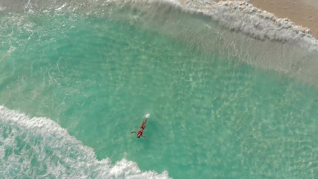 Beautiful woman floating on ocean water in Playa Delfines beach, Cancun, Mexico