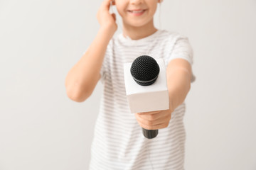 Little journalist with microphone on white background