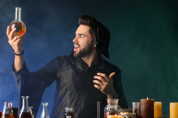Male alchemist making potion on dark background