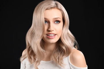 Young blonde with beautiful hair on dark background