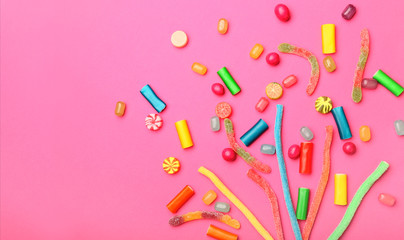 Assortment of sweet candies on color background