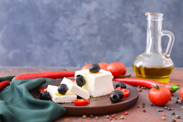 Tasty feta cheese with vegetables and spices on table