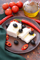 Tasty feta cheese with vegetables and spices on plate