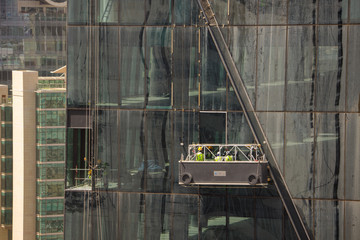 Group of workers cleaning the windows of a high rise building, dangling from secure ropes. Washing the windows of a skyscraper, view of clean and dirty windows. © Ovidiu
