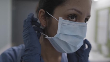 Closeup of nurse applying mask in slow motion during the corona virus pandemic. - Powered by Adobe