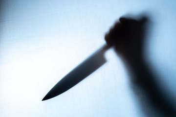 Blurred shadow of a hand holding a big and sharp knife - obrazy, fototapety, plakaty