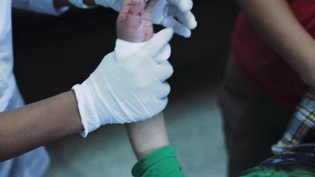 Doctor healing cut of a boy who cut his thumb.