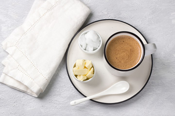 Bulletproof coffee in white ceramic cup blended with butter and coconut oil. paleo, ketogenic drink breakfast. flat lay