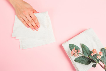  Beautiful young woman's hands with  white care  towel   on pastel pink background .