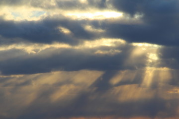 The sun at sunset or dawn behind the clouds, shines through. The sun's rays in the sky.