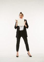 A young girl in office clothes is holding a white blank sheet of paper.