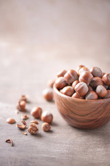 Hazelnuts in wooden bowl on wood textured background. Copy space. Superfood, vegan, vegetarian food concept. Macro of hazelnut, selective focus. Healthy snack.