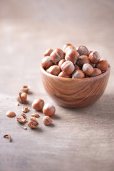 Hazelnuts in wooden bowl on wood textured background. Copy space. Superfood, vegan, vegetarian food concept. Macro of hazelnut, selective focus. Healthy snack.