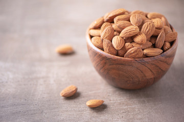 Almond nuts in wooden bowl on wood textured background. Copy space. Superfood, vegan, vegetarian...