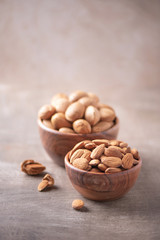 Almond nuts in wooden bowl on wood textured background. Copy space. Superfood, vegan, vegetarian food concept. Macro of almond nut texture, selective focus. Healthy snack