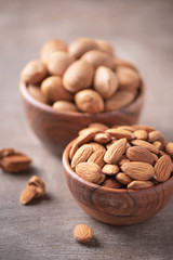 Almond nuts in wooden bowl on wood textured background. Copy space. Superfood, vegan, vegetarian food concept. Macro of almond nut texture, selective focus. Healthy snack