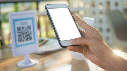 Code payment , online shopping , cashless technology concept. Coffee shop accepted digital pay without money , plastic tag on table and hand using mobile phone application to scan qr code.