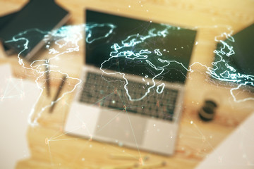 Abstract creative world map on modern laptop background, international trading concept. Multiexposure