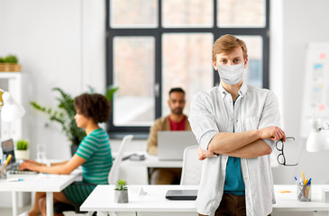 business and people concept - man with glasses wearing protective medical mask for protection from virus disease at office