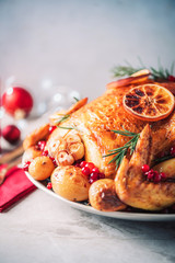 Roasted chicken with festive decoration, candles, light bokeh on concrete background. Traditional New Year holiday or Christmas celebration dish. Friends or family dinner. Festive Christmas table.