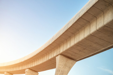 Fototapeta premium Looking up skytrain viaduct in downtown with blue clear sky. A mass transit train line in progress.