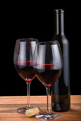 isolated on black two glasses and bottle with red wine