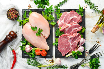 Veal meat and chicken breast with spices. Top view. On a white wooden background. Free space for your text.