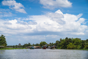 Three towing boats are pulling sand carriers in the middle of the river on a clear day.
