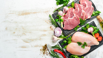 Veal meat and chicken breast with spices. Top view. On a white wooden background. Free space for your text.