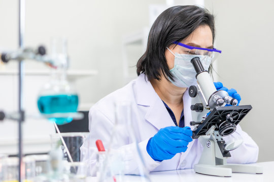 Scientis using microscope to work in lab.
