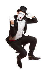 Portrait of a male mime artist performing, isolated on white background. Symbol of unpleasantly surprised, upset, falling, squatting, sad