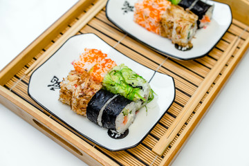 Several sushi on a white plate standing on a white background
