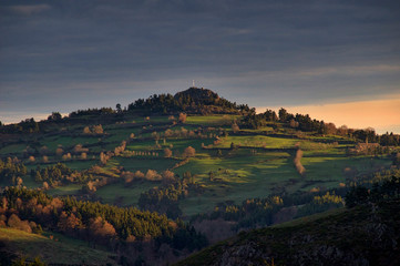 sunrise seen from saint lucie , lozere , france. showing la roc de peyre. feilds with a white cross on the hill top.