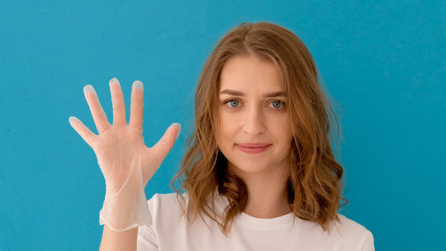 Woman puts on rubber gloves for protection on blue background