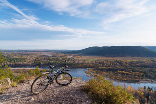 the bike is already on the trail with a view of the mountains and the river flowing in the valley, around the forest. the concept of tourism and a healthy lifestyle © zaktatyana