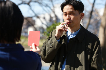 レッドカードを出される歩きタバコの男性