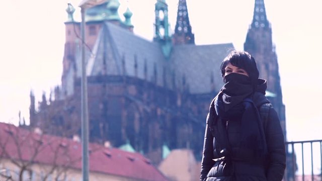 A woman in black clothes and a black mask on the background of the castle. Fashion during the pandemic of viral infection. Clothing that protects against viruses.