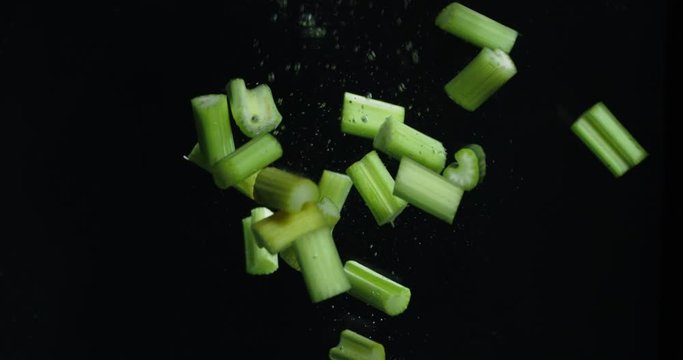 Pieces of celery falling into the water with air bubbles.