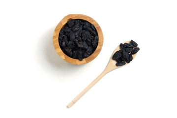 a wooden bowl of raisins and a wooden spoon isolated on white background flat lay