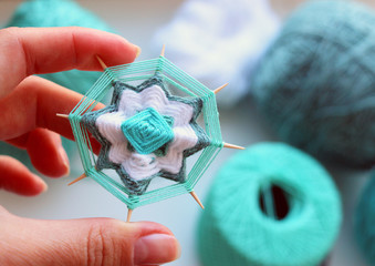 Wicker mandala made of blue yarn on wooden toothpicks. Flower pattern.