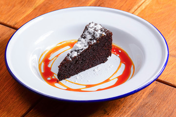 A slice of delicious chocolate cake. Piece of cake on a white plate with caramel. Sweet food.