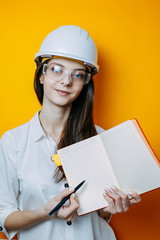 Woman engineer in white helmet and glasses. Safety poster. Woman in helmet holds notebook and pen.