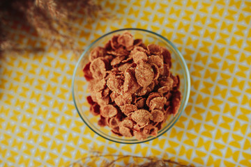 Healthy nutrition, healthy food on the table, dark cereal in the glass bowl on yellow table.