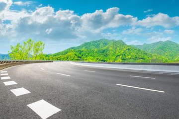 Asphalt road and green mountain nature landscape on sunny day.