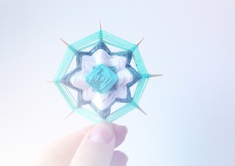 Wicker mandala made of blue yarn on wooden toothpicks. Flower pattern.