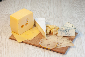 different types of cheese Roquefort cheese, walnut cheese, brie, on a wooden board.