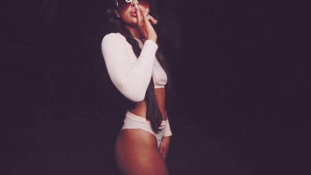Cute and sexy brunette girl wearing pink long sleeve crop top and panties set and sunglasses dancing, smiling, flirting during summer evening - video in slow motion