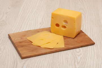 Piece of cheese and sliced cheese on a wooden board